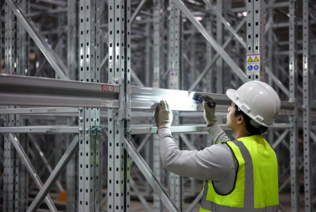 Gecertificeerde inspecteur controleert palletstelling op stabiliteit en belasting in magazijn